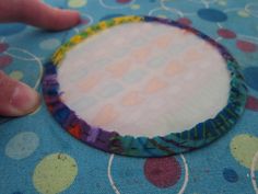 a person is holding a piece of fabric on top of a blue table cloth with circles and dots