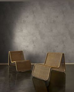 two wicker chairs sitting next to each other in front of a gray wall and floor