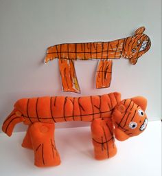 two orange stuffed animals sitting next to each other on a white surface with cut outs