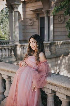 a woman in a pink dress leaning on a wall