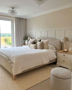 a large white bed sitting in a bedroom next to a window