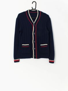 Vintage navy blue preppy cardigan. This cute cardigan is a lovely navy blue with white and red stripes around the opening, cuffs and tops of hand pockets. This varsity college style cardigan will elevate any outfit! The cardigan is made from a soft, lightweight material.  Our recommended size: XS to small  Label says: No size  Condition: Very good  Material: No care label  Measurements in inches: Pit to pit: 18.5 Shoulders: 18 Front length: 24 Back length: 23.5 Sleeve length: 20.5 Hem unstretche Classic Navy Cardigan With Ribbed Cuffs, Long Sleeve Cardigan With Striped Cuffs For Winter, Winter Long Sleeve Cardigan With Striped Cuffs, Casual Winter Cardigan With Striped Cuffs, Blue Winter Sweater With Striped Cuffs, Winter Cardigan With Striped Cuffs And Long Sleeves, Navy Cardigan With Ribbed Cuffs For Fall, Navy Cotton Winter Cardigan, Navy Cotton Cardigan For Winter