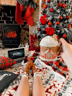 a woman laying on top of a blanket next to a christmas tree and fire place