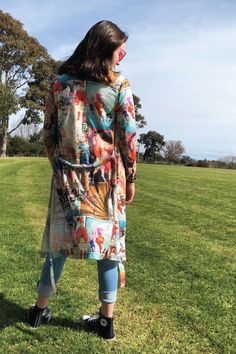 a woman standing on top of a lush green field next to a tree and grass covered field