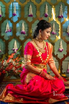 a woman in a red and gold dress sitting down