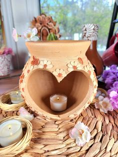 a heart shaped vase sitting on top of a table next to some candles and flowers