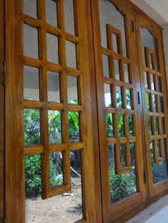 an open window with wooden frames on the side of a wall in front of trees