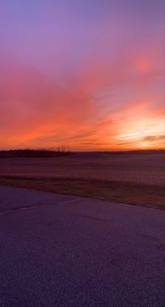 the sun is setting over an empty field with no people in it, and there are clouds