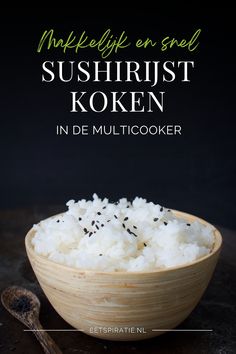 a wooden bowl filled with white rice on top of a black table next to a spoon