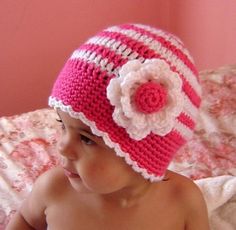 a small child wearing a pink and white crocheted hat with flowers on it