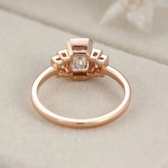 our Bezel Set Art Deco Unique Emerald Cut Moissanite Cluster Baguette Engagement Ring in 14K Rose Gold. This exquisite ring features a dazzling emerald-cut Moissanite stone surrounded by a cluster of sparkling baguette diamonds, all set in a beautiful rose gold band. Rose Gold Square Cut Wedding Rings, Art Deco Rectangular Baguette Diamond Ring, Elegant Rectangular Ring With Rose Cut Diamonds, Elegant Rectangular Rings With Rose Cut Diamonds, Rose Gold Baguette Diamonds Wedding Ring, Elegant Rectangular Rose Cut Diamond Rings, Baguette Cut Diamond Ring With Rose Cut Diamonds, Rose Gold Moissanite Diamond Ring With Baguette Cut, Rose Gold Moissanite Jewelry With Baguette Cut