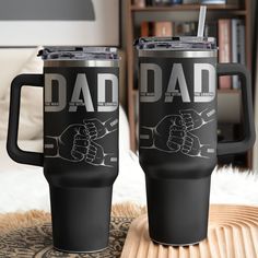 two black coffee mugs sitting on top of a table