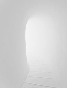 an empty white room with stairs leading to the light