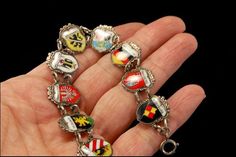 "This is a very beautiful, very unique and vintage GERMAN SILVER travel shield charm bracelet (17.3g). The bracelet has marvelous 9 charms with German shield and silver (bottom has 800 REU). The bracelet has a very exotic and elegant feel to it. It measures 7 3/4\" long. The bracelet is in very good condition. 0.7 A96346" Unique Metal Charm Bracelet Collectible, Unique Silver Jewelry With Vintage Charm, Ornate Jewelry Charms For Collectors, Ornate Collectible Charms Jewelry, Unique Silver Bracelets With Charms, Handmade Silver Jewelry As Souvenir, Handmade Silver Jewelry Souvenir, Handmade Silver Jewelry For Souvenir, Vintage Silver Jewelry With Coat Of Arms