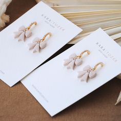 two pairs of earrings sitting next to each other on top of a white piece of paper