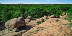 large rocks on the side of a hill with trees in the background and blue sky above