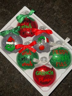 six christmas ornaments with the grinch on them are sitting in a tray and tied together