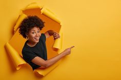 a woman holding a yellow object in her right hand and pointing to it with both hands