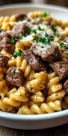 pasta with meat and parmesan cheese in a white bowl on a wooden table