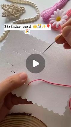 someone is making a card out of paper and thread