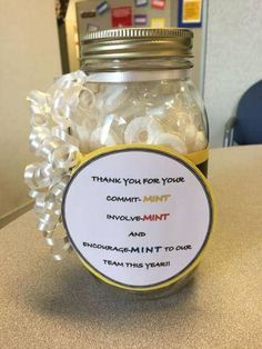 a jar filled with white candy sitting on top of a table next to a sign that says thank you for your commit mint