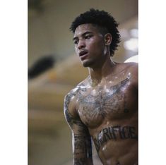 a shirtless man with tattoos on his chest and arms is looking off to the side