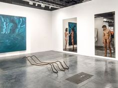 three paintings hang on the wall in an art gallery, one is naked and another has no shirt