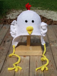 a crocheted chicken hat sitting on top of a wooden stand