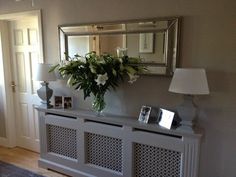 a vase filled with flowers sitting on top of a white dresser next to a mirror