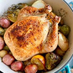 a whole chicken in a pot with potatoes and brussel sprouts