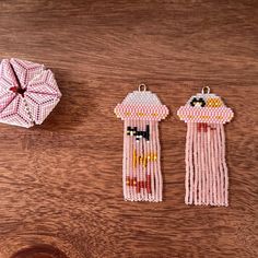 two pieces of beaded art sitting on top of a wooden table