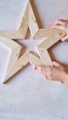 two hands are holding wood pieces in the shape of a star on a white surface