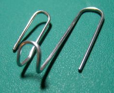 a pair of metal hooks sitting on top of a green surface