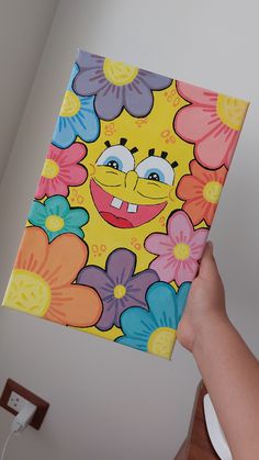 a person holding up a colorful flowered box with a smiley face painted on it