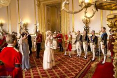 a group of people standing in front of a room filled with gold and red decorations