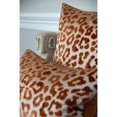 an orange and white leopard print pillow sitting on top of a chair next to a stuffed animal