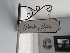 a sign hanging from the side of a white wall next to a doorway and framed pictures