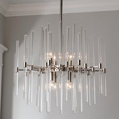 a chandelier with clear glass tubes hanging from it's center point in a room