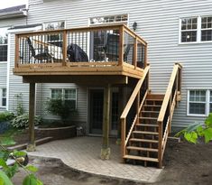 a wooden deck with stairs leading up to the upper floor and second story above it