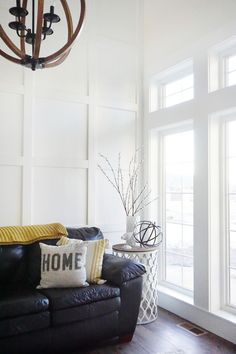 a living room with black leather couches and white walls