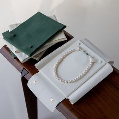 a table topped with a white plate covered in pearls next to a green bag and napkins