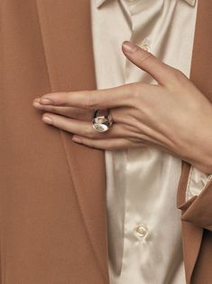 a close up of a person's hand wearing a ring on their lapel