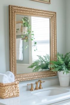 a bathroom sink with a mirror above it and a potted plant on the counter