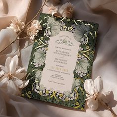 the wedding card is surrounded by flowers and satin material, with an ornate frame on it