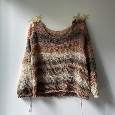 an old sweater hanging on the wall with some clothes pins attached to it and two strings