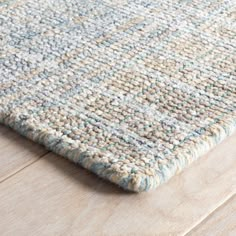 an area rug with blue and white colors on top of a wooden floor in a living room