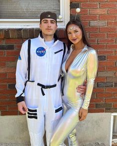 a man and woman dressed up as astronauts posing for a photo in front of a brick building