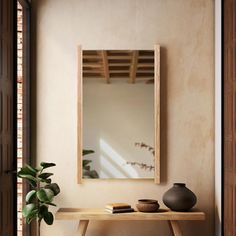 a wooden table sitting under a mirror next to a potted plant