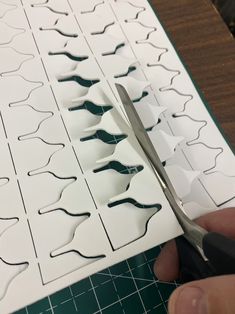 someone cutting out some paper with scissors on top of it and another piece of cut outs in the background