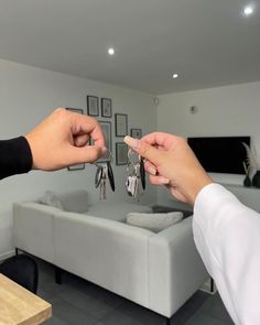 two people exchanging keys to each other in front of a living room with white furniture